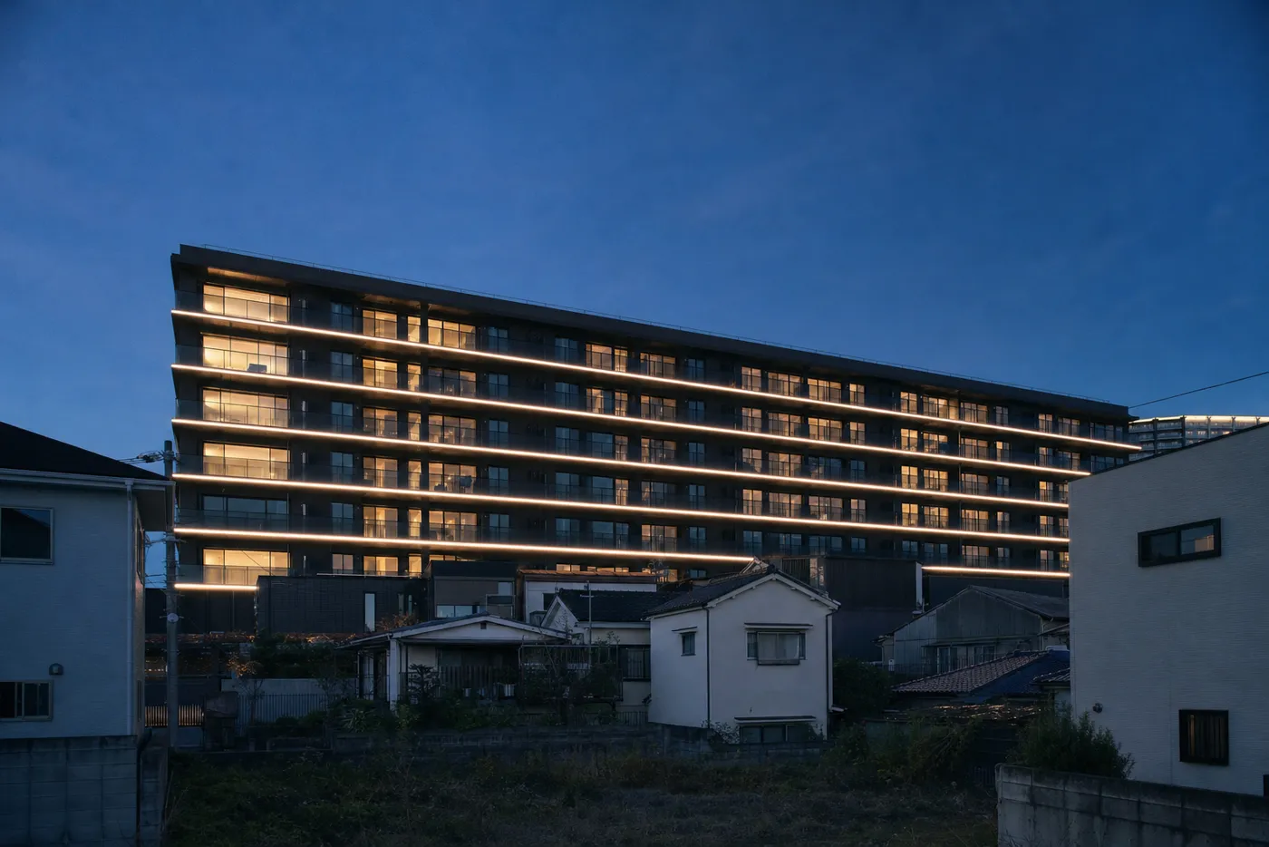 夕暮れのマンション。各階に細い光の線が走っている(イメージ写真)