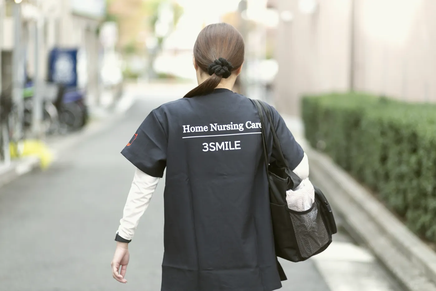 訪問看護の制服で歩くスタッフの後ろ姿(関連会社3SMILE)