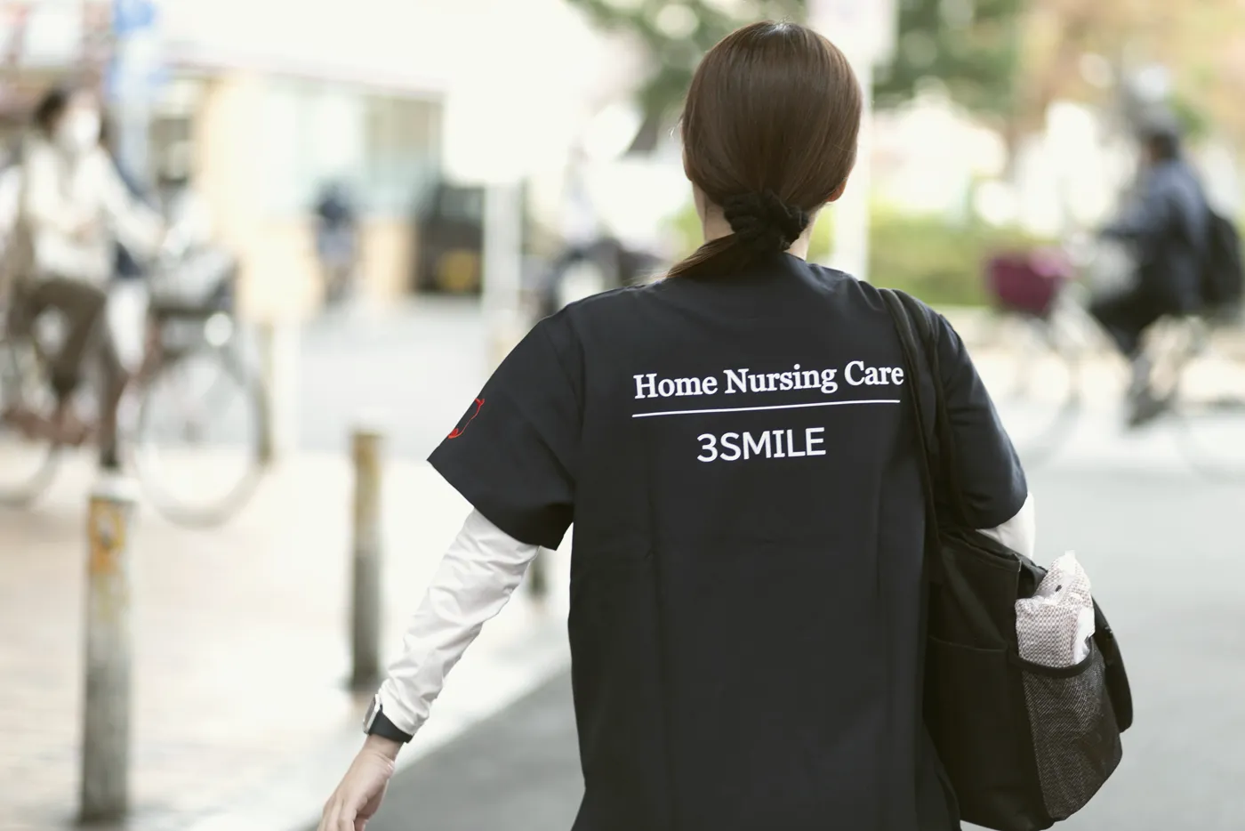 3SMILEのロゴが入った制服で街を歩くスタッフの後ろ姿