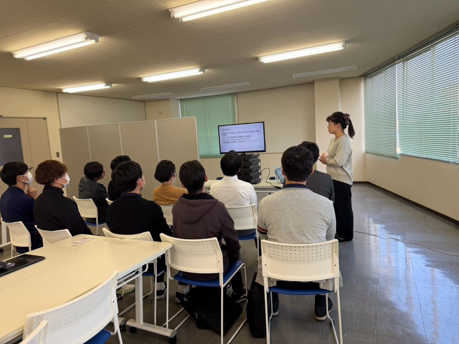 研修室でスタッフが並んで説明を聞いている社内勉強会の様子