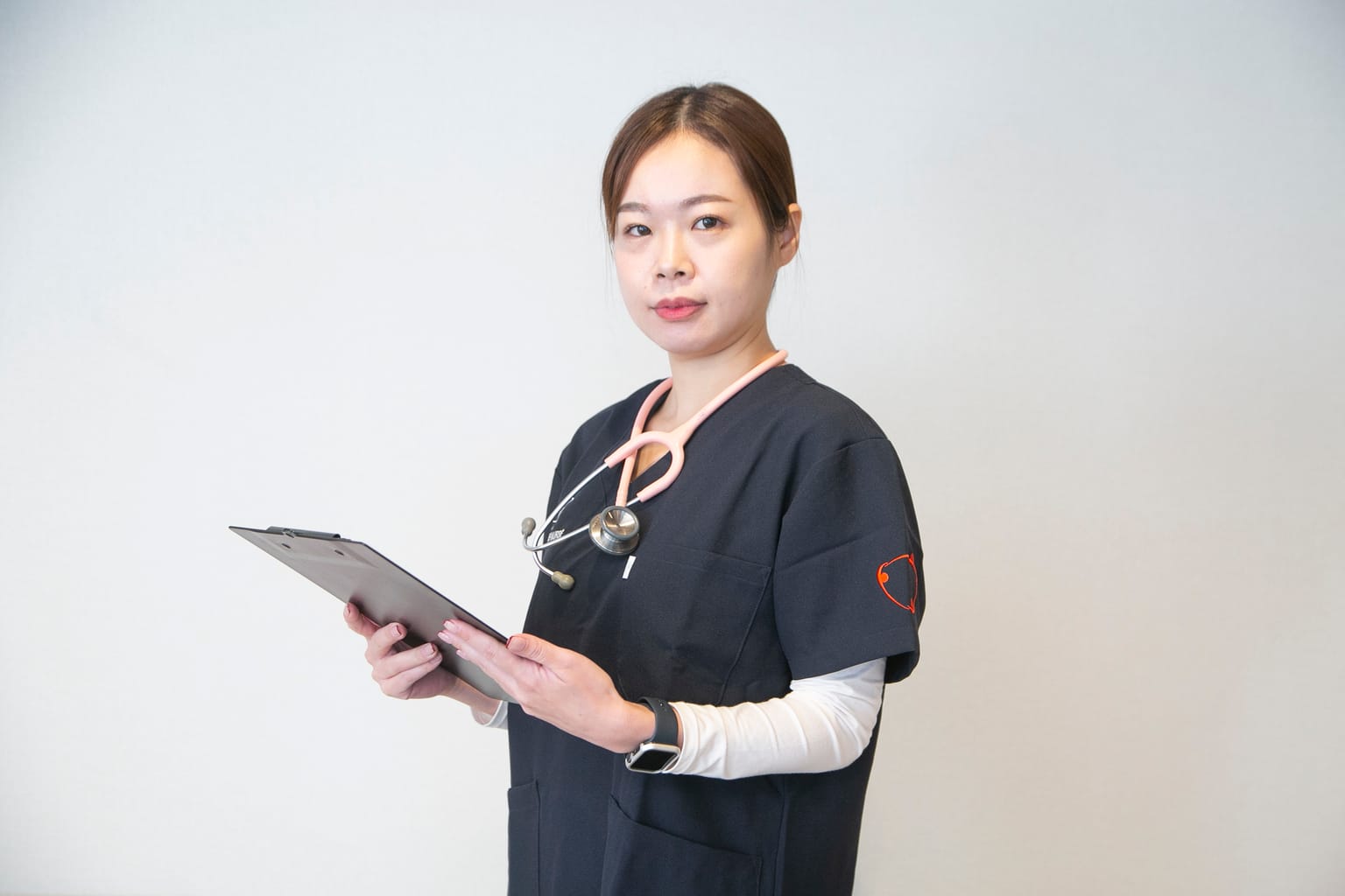 クリップボードを持って記録を確かめる訪問看護師(関連会社3SMILEの訪問看護の撮影より)