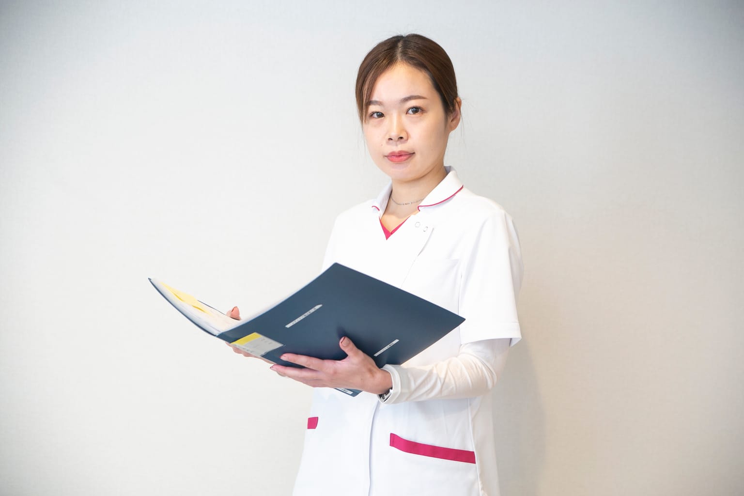 書類のファイルを開いて内容を確かめる看護師(関連会社3SMILEの訪問看護の撮影より)
