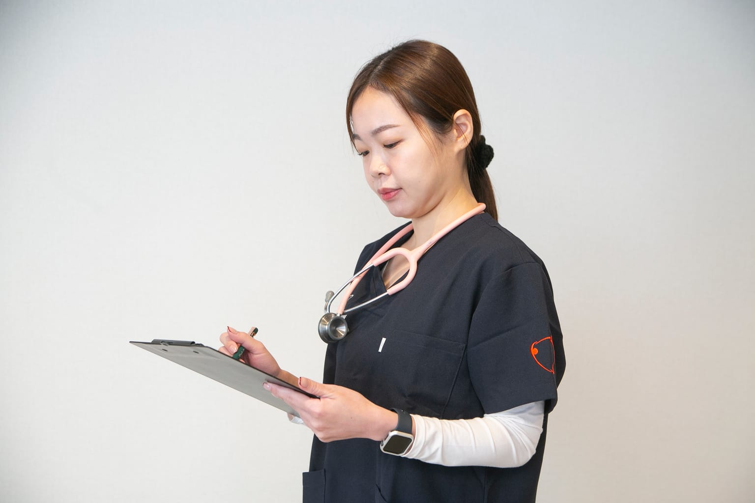 クリップボードに記録を書き込む訪問看護師(関連会社3SMILEの訪問看護の撮影より)