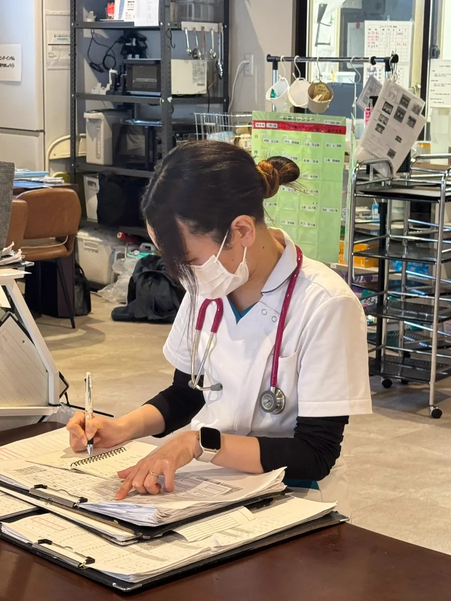 机で記録用紙に書き込む看護師