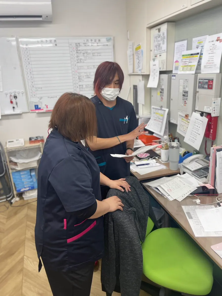 事務所で書類を見ながら話す職員2人